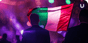 A man in a suit faces away from the camera, standing in front of an Italian flag