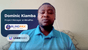 A man wearing a blue polo shirt participating in a video call, identified as Dominic Kiamba, Project Manager at BlindPax, with the logos of BlindPax and UserWay visible on the screen.