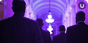 A shot of 4 people walking down a hall, their silhouettes in black and the hallway lit in purple