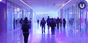 Groups of college students walk down a pink and lavender hallway with large windows and columns