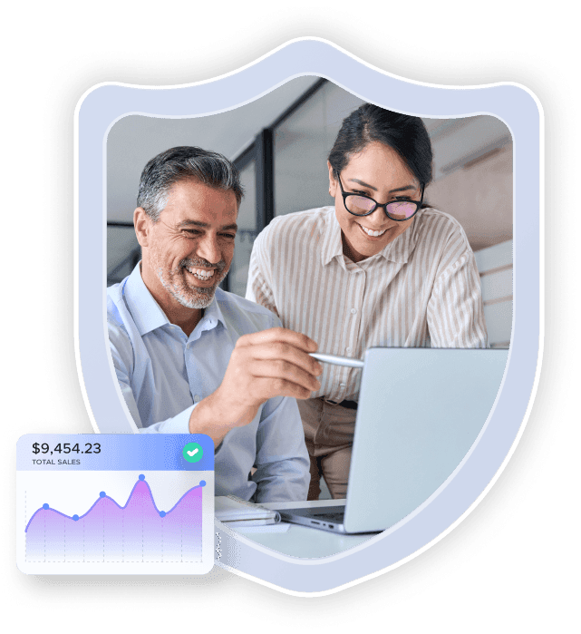 Two colleagues smiling as they look at a laptop with a sales figures chart at the bottom left