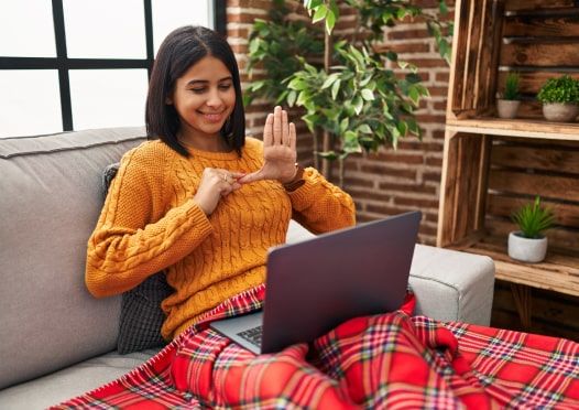 Woman wearing yellow sweater working on laptop